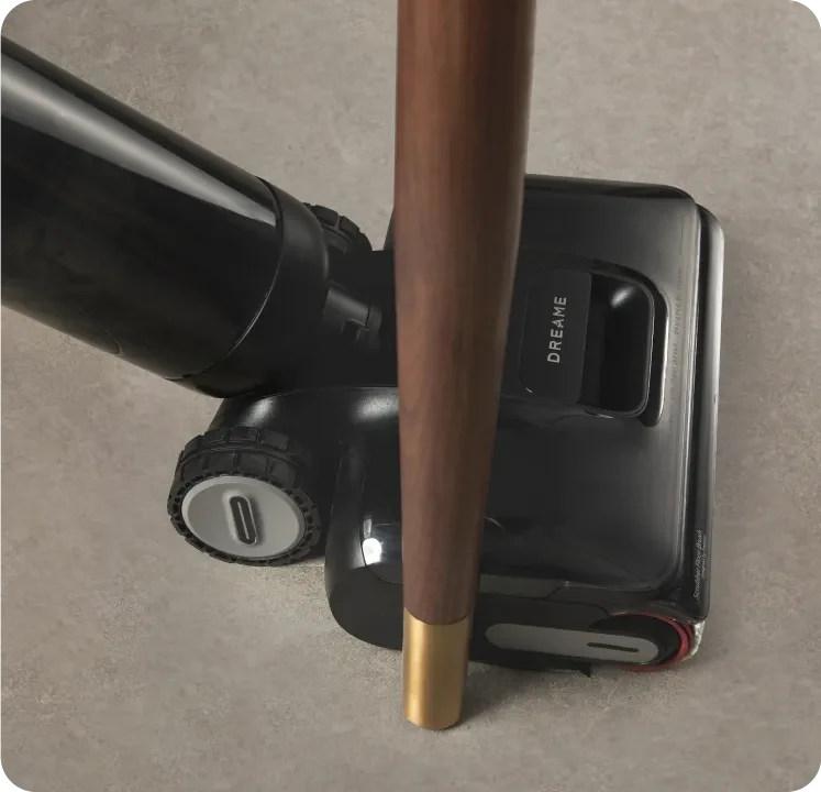 Tête du Dreame H12 Pro FlexReach près du pied d’un meuble