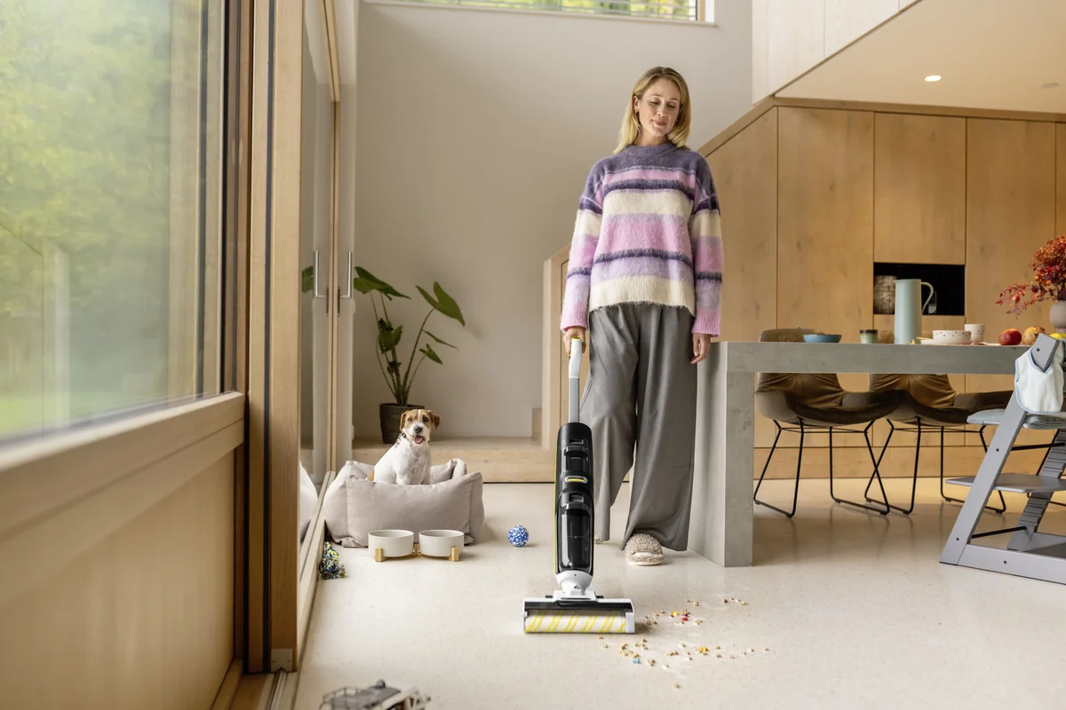 Une personne utilise le Kärcher FCV 4 près d’une table et d’un couchage pour chien.